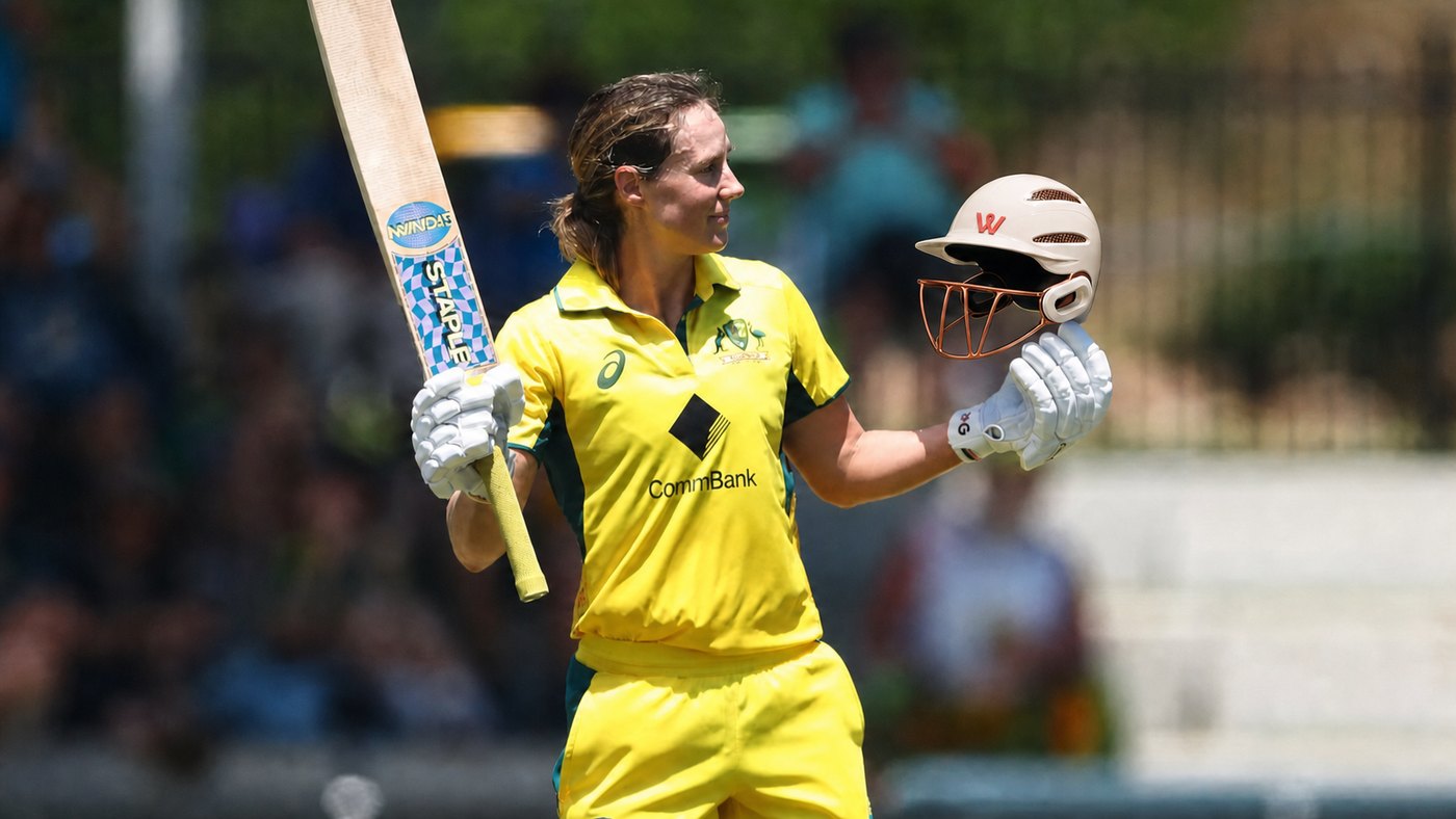 A leading Australian cricketer raising her bat and holding a WaughHead helmet